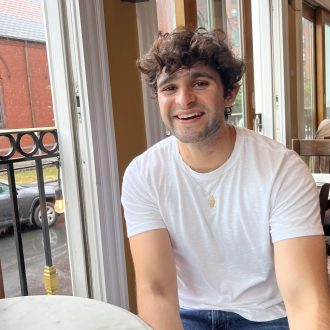 Close-up of Darius Atefat-Peckham sitting at a table and smiling.