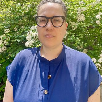 Author photo of Meredith Nnoka. Author wearing black framed glasses and a blue top.