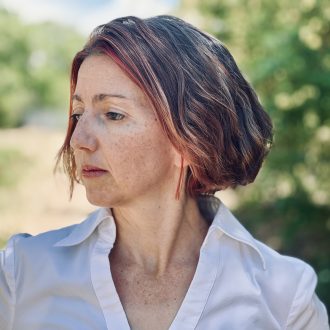 Author photo of Grace Spulak. Author wears white button v-neck shirt.
